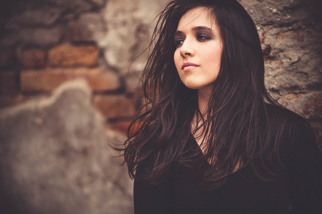 girl in black leaning on a brick wall with wind in hair_resize-2